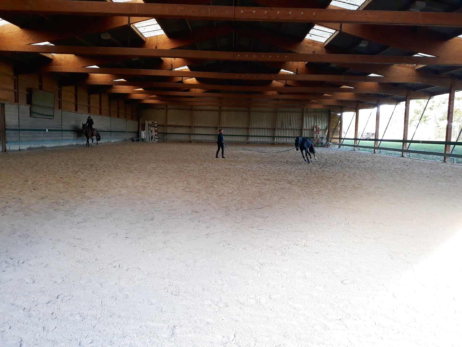 Manège couvert aux Écuries du Bois Clos, centre équestre et écurie de propriétaires dans le pays de Gex Manège couvert aux Écuries du Bois Clos, centre équestre et écurie de propriétaires dans le pays de Gex